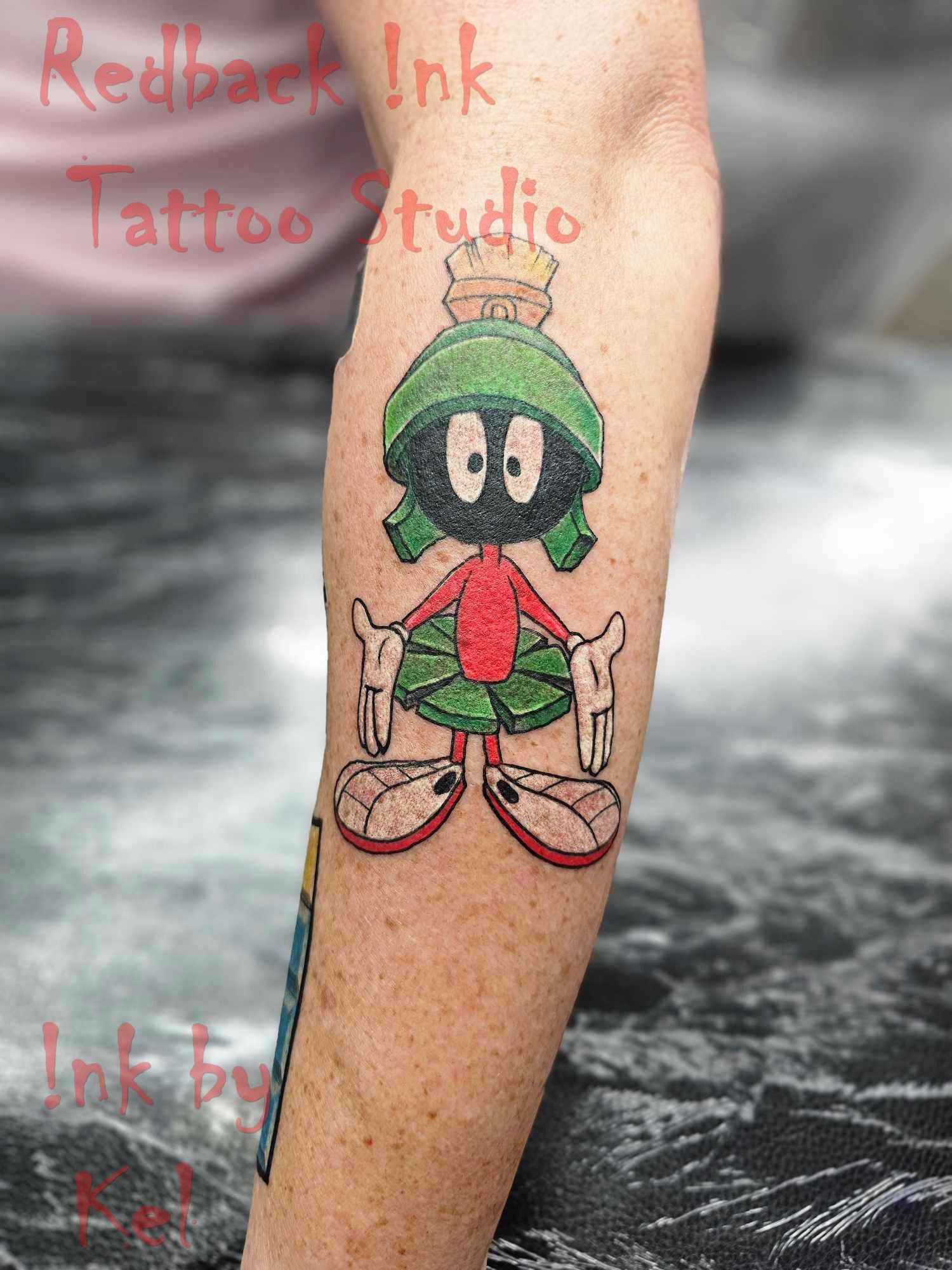 Marvin the Martian tattoo on an arm. Green helmet, red suit, white gloves, on a person's arm.