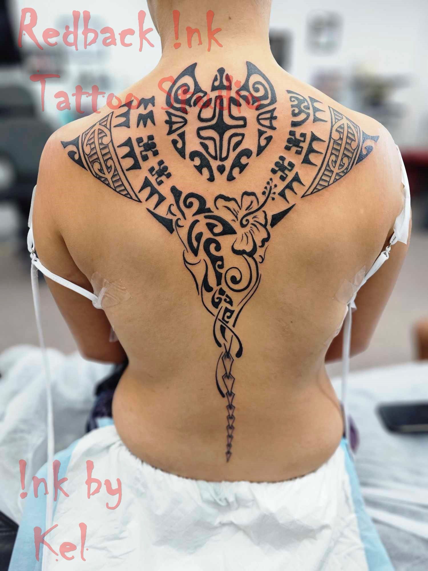 Tattoo of a black manta ray on a person's back, with tribal patterns. Redback Ink logo visible.