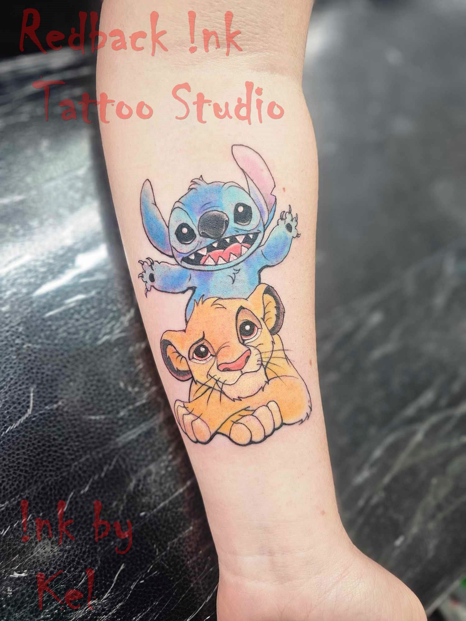 Tattoo of Stitch and Simba; blue Stitch smiles above orange Simba on an arm, in a studio setting.