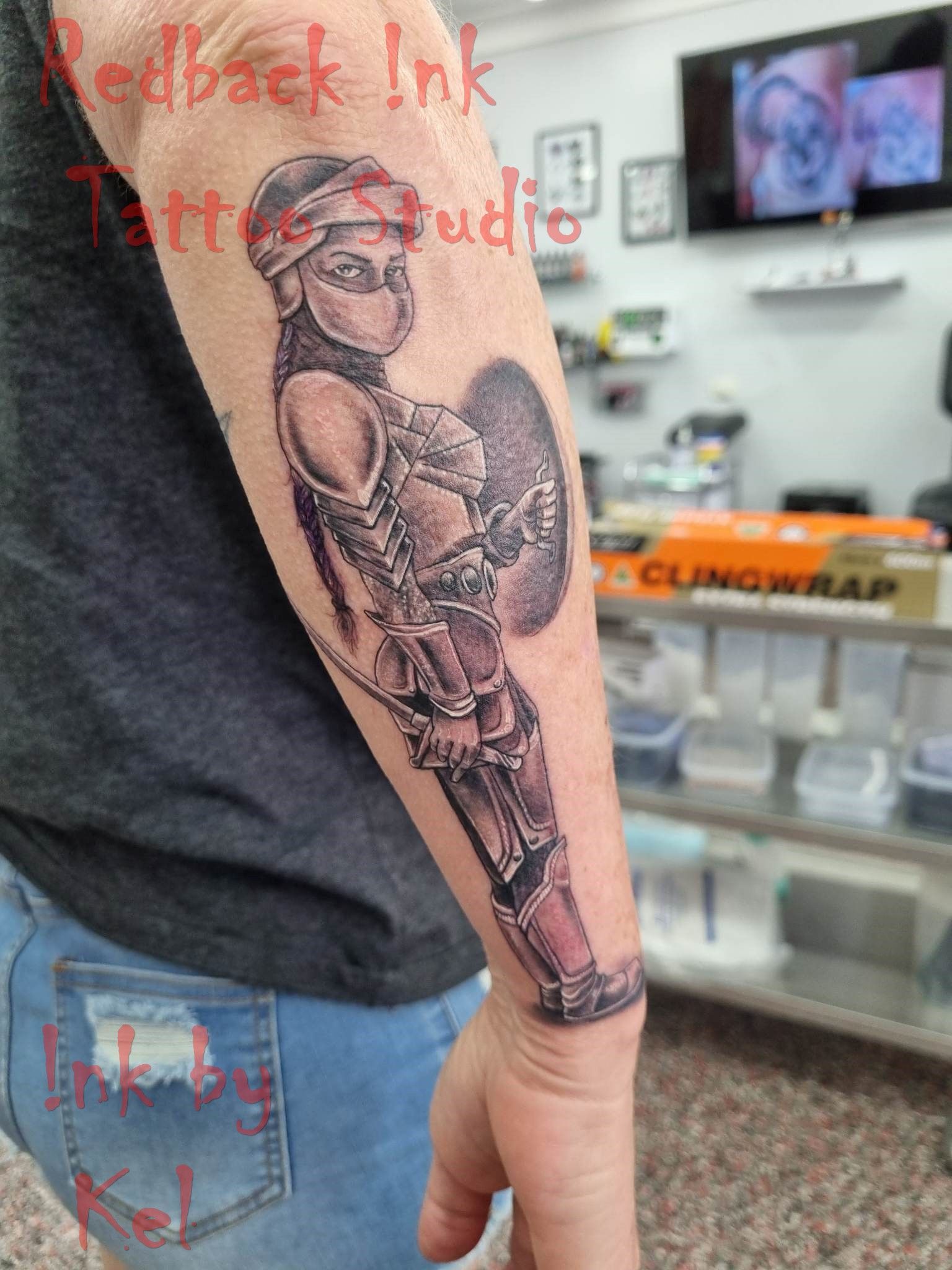 Tattoo of a warrior woman with a shield and sword on a person's forearm. In a tattoo studio.