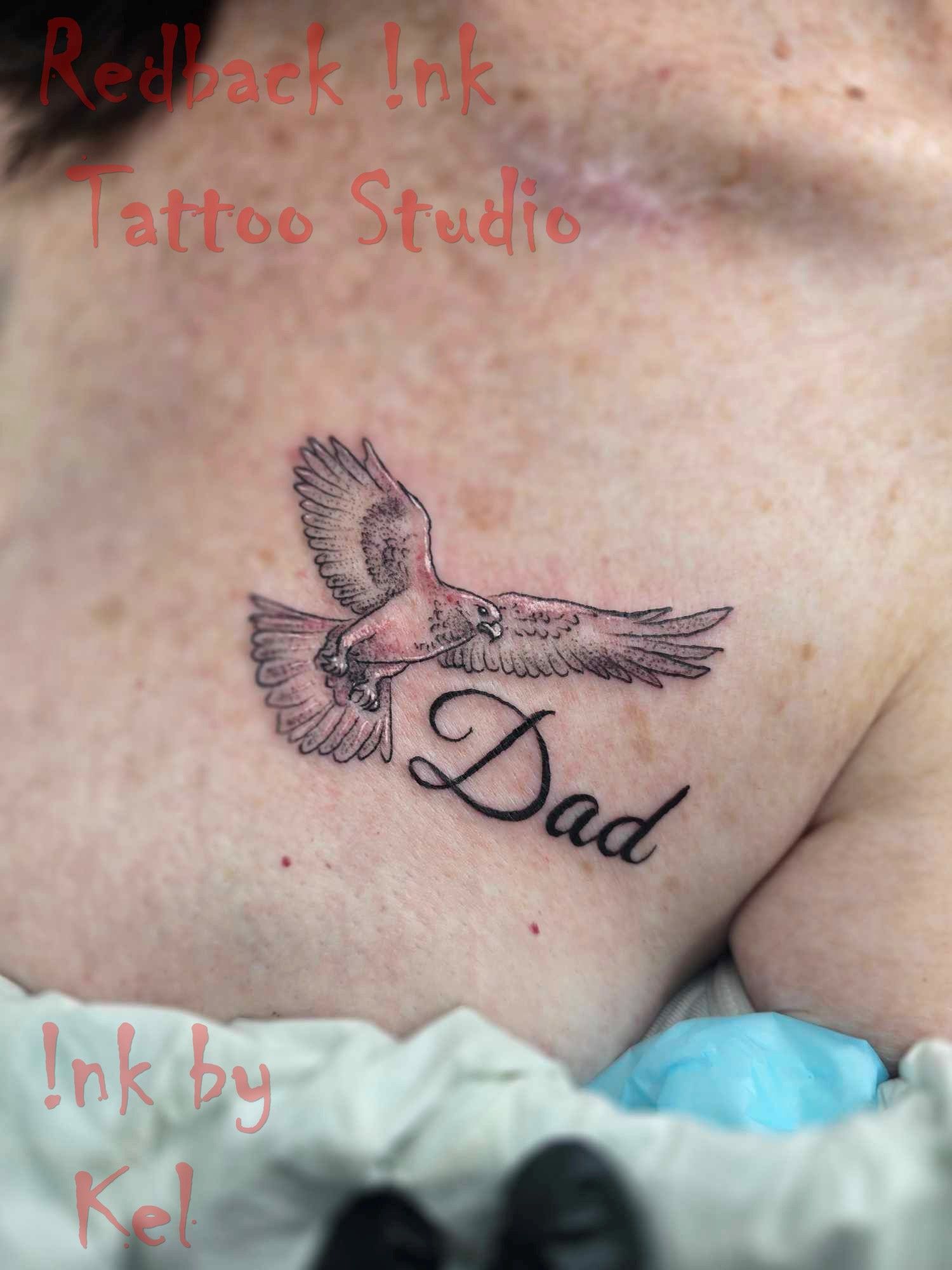 A black and white tattoo of a flying bird with the word 
