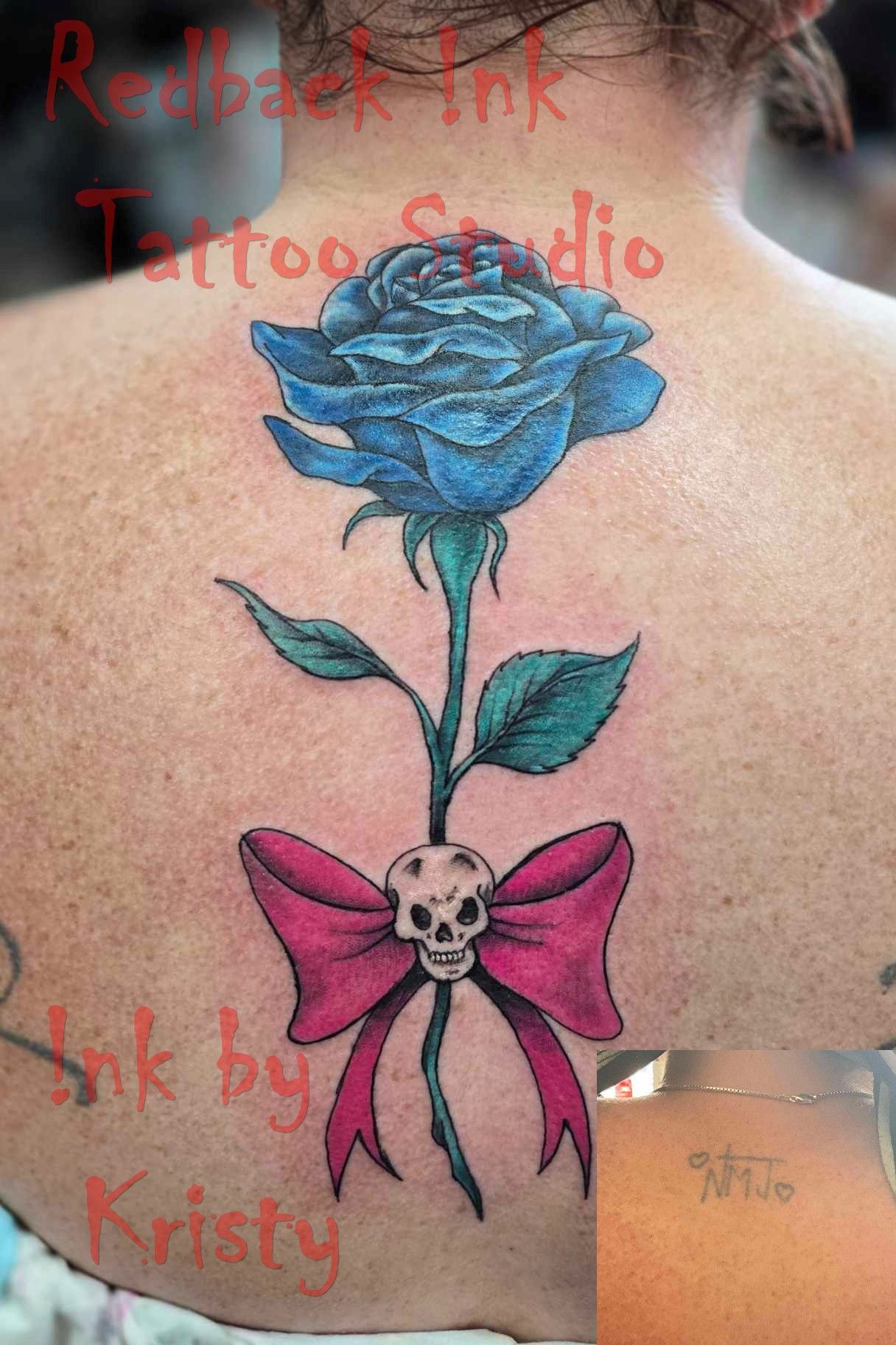 Blue rose tattoo with pink bow and skull on a back — Redback !nk Tattoo Studio in Kawana, QLD