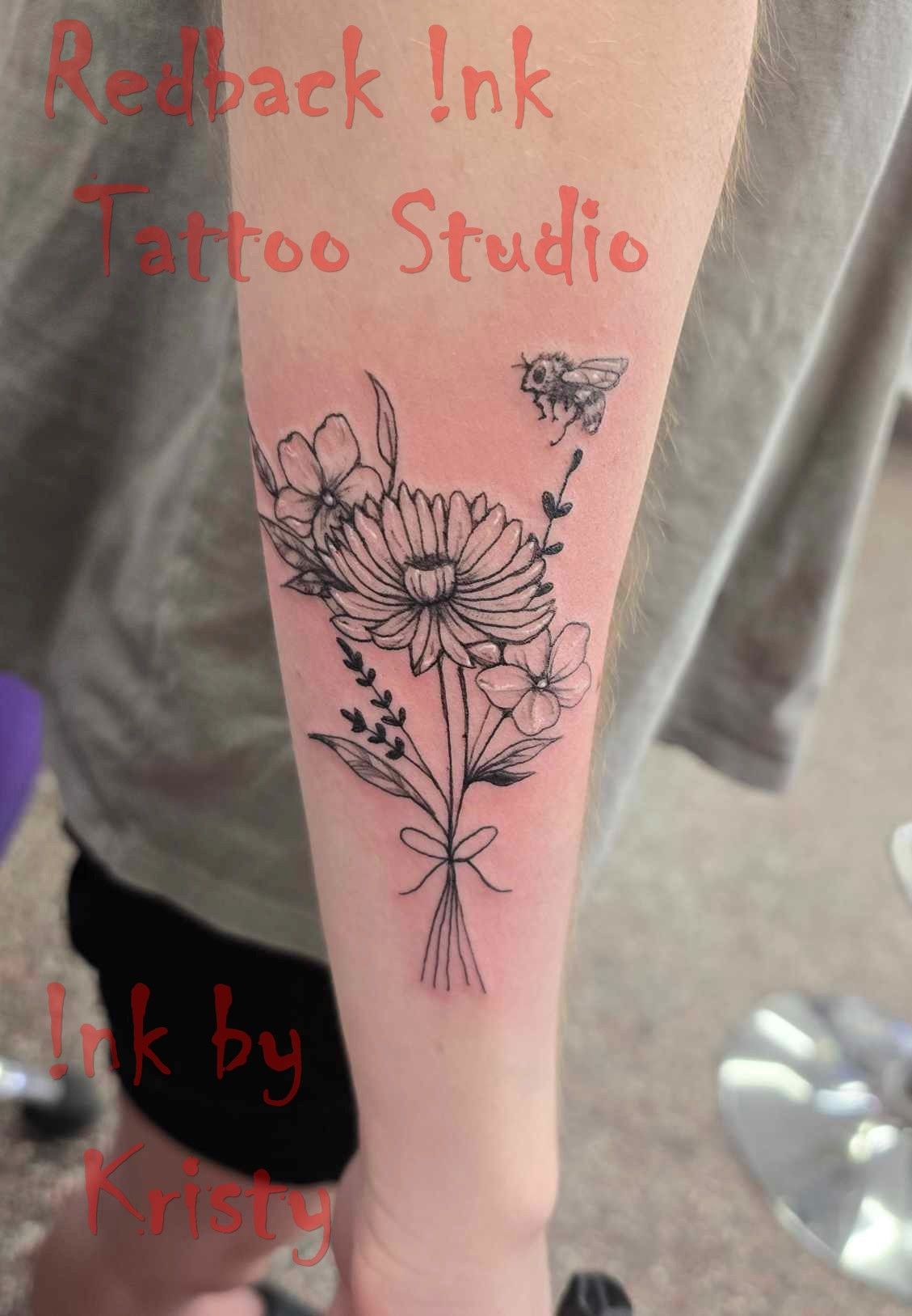 Black ink floral tattoo on a forearm, with a bee, tied with a bow — Redback !nk Tattoo Studio in Kawana, QLD