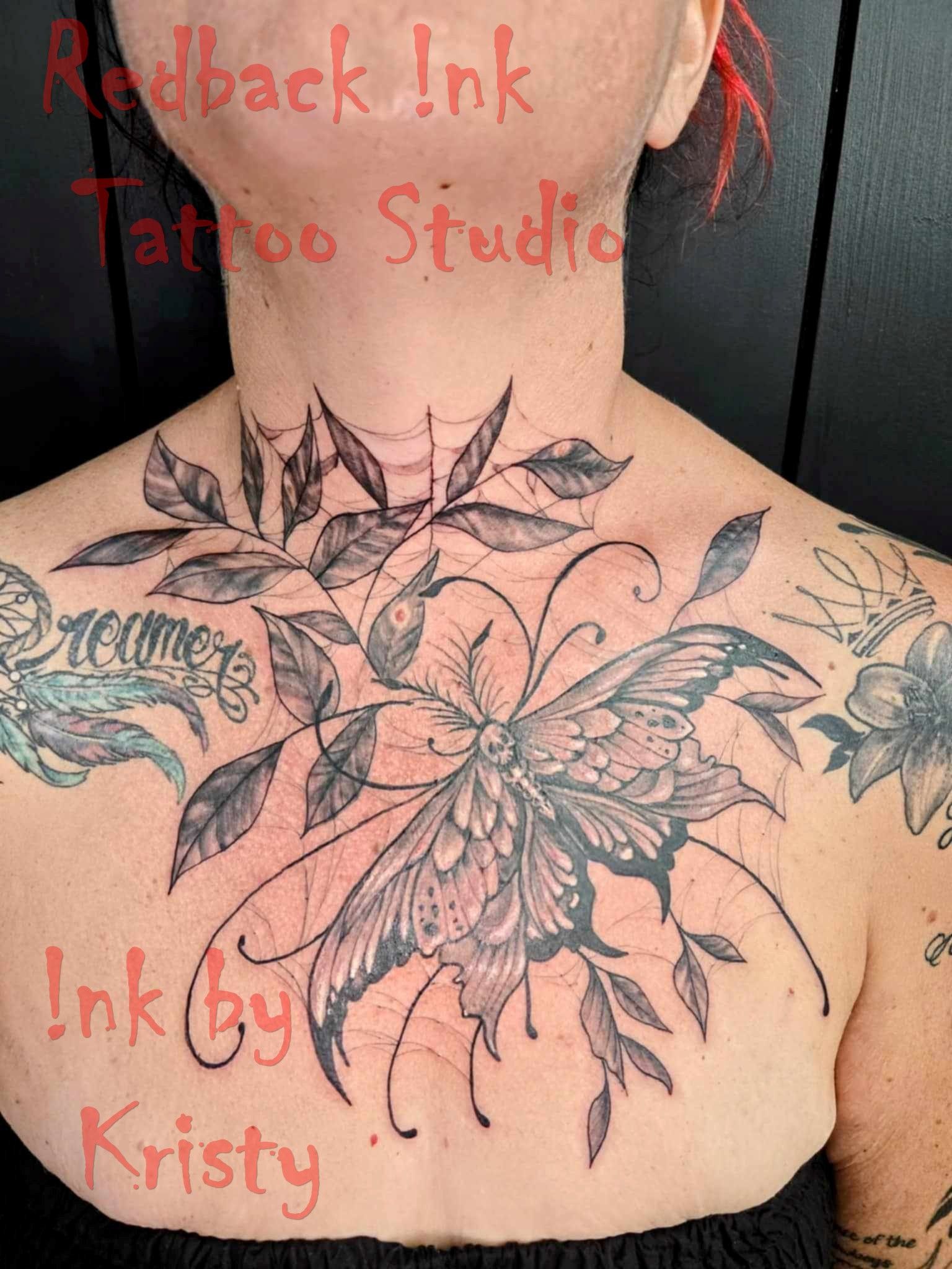 Chest tattoo of a detailed butterfly with leafy vines, with some older tattoos visible on shoulders — Redback !nk Tattoo Studio in Kawana, QLD