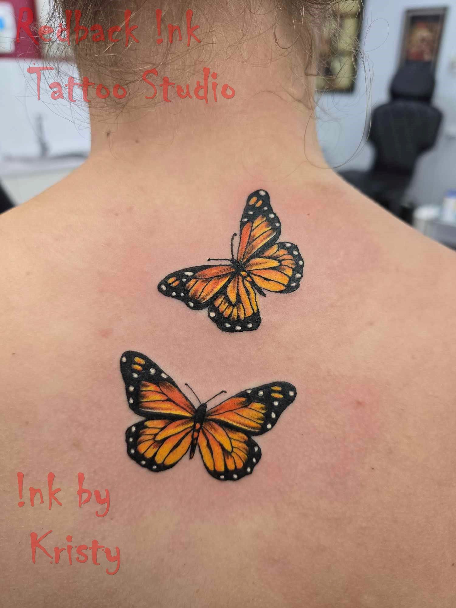Two orange monarch butterfly tattoos on a person's upper back — Redback !nk Tattoo Studio in Kawana, QLD