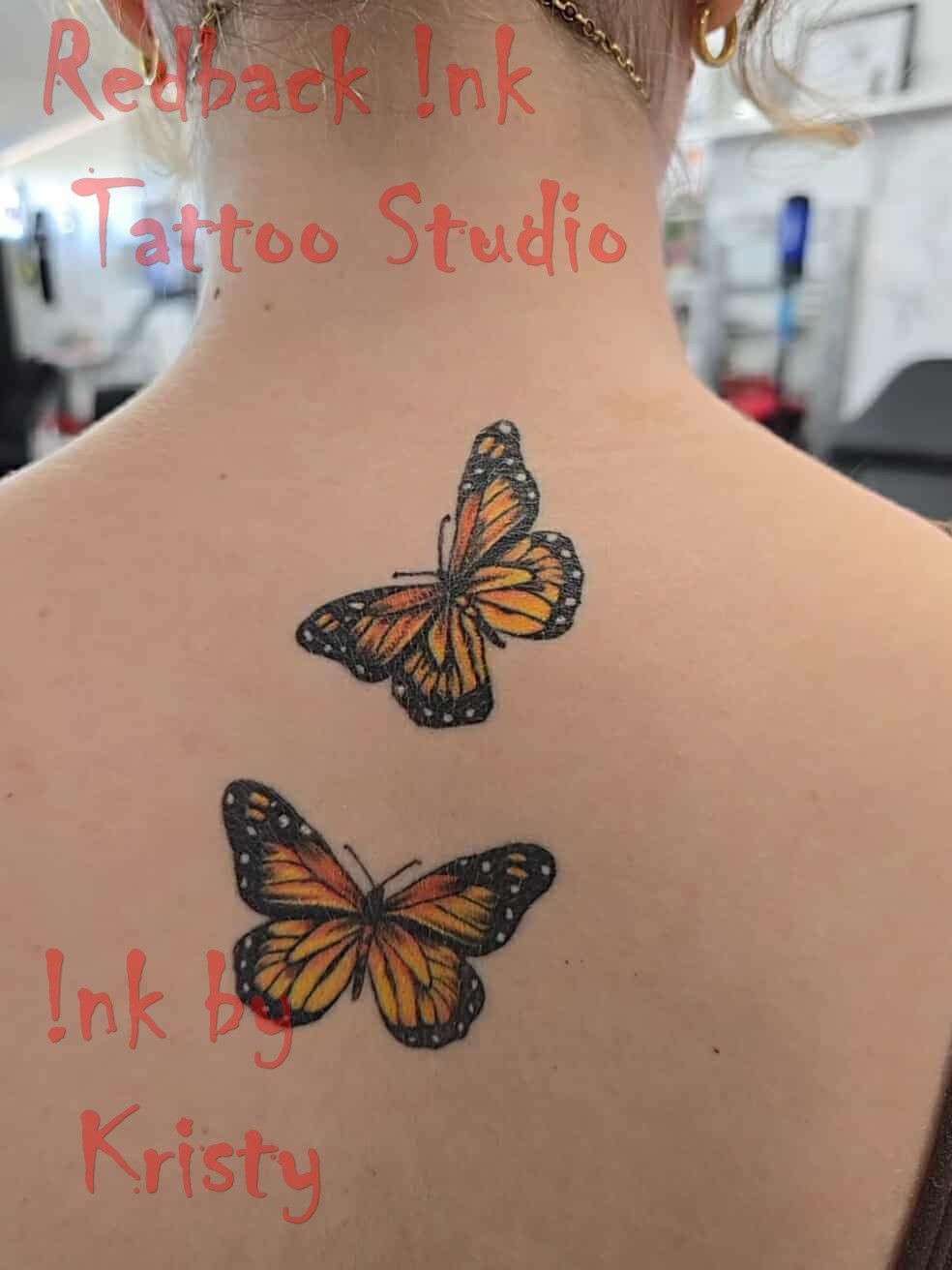 Two orange and black butterfly tattoos on a person's upper back, in a studio setting — Redback !nk Tattoo Studio in Kawana, QLD