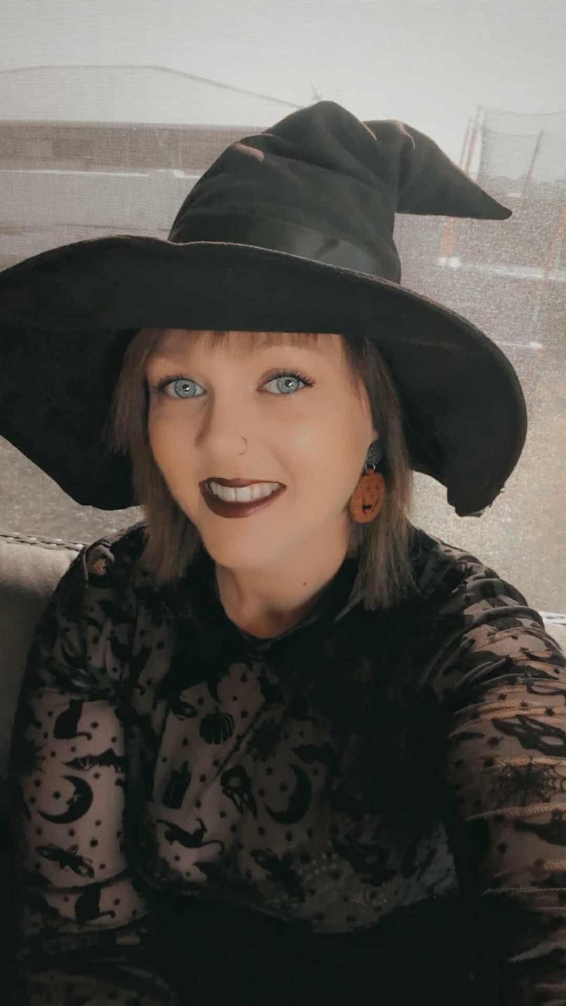 Woman in witch hat and costume smiles — Redback !nk Tattoo Studio in Kawana, QLD