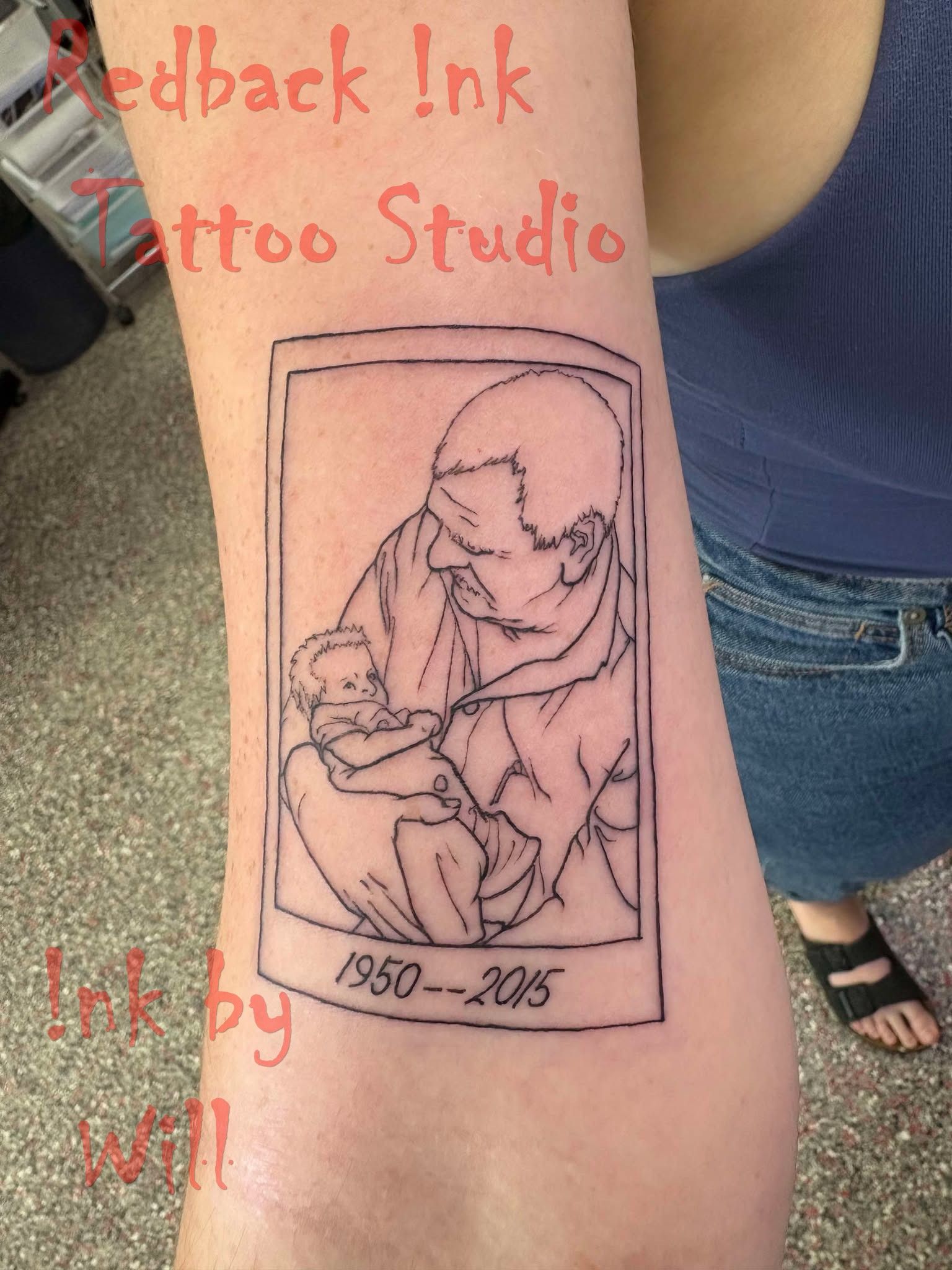 Tattoo of a person holding a baby inside a polaroid frame, with dates 1950-2015.