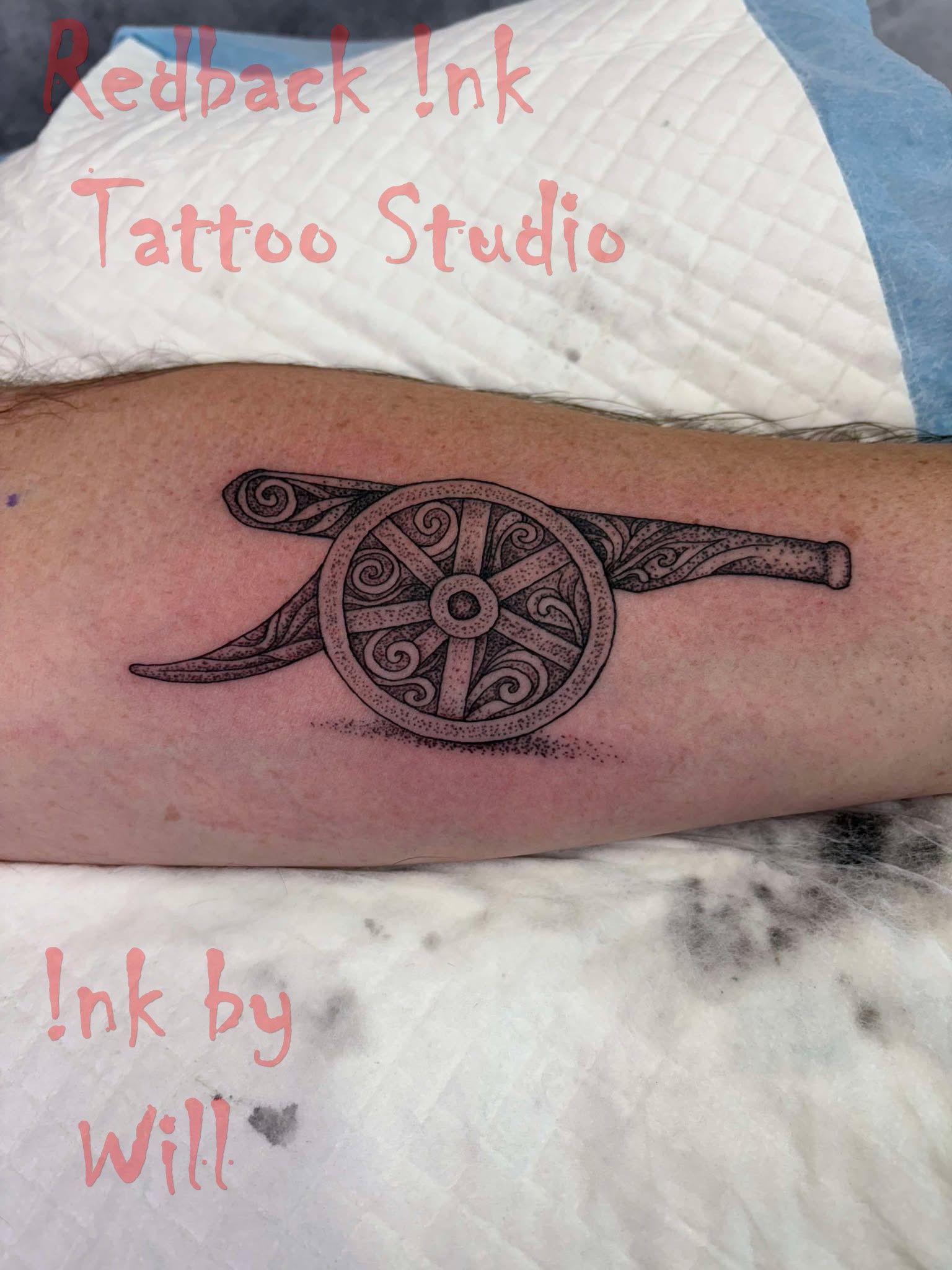 Tattoo of the Arsenal cannon on a forearm. Black ink on white skin, studio setting.
