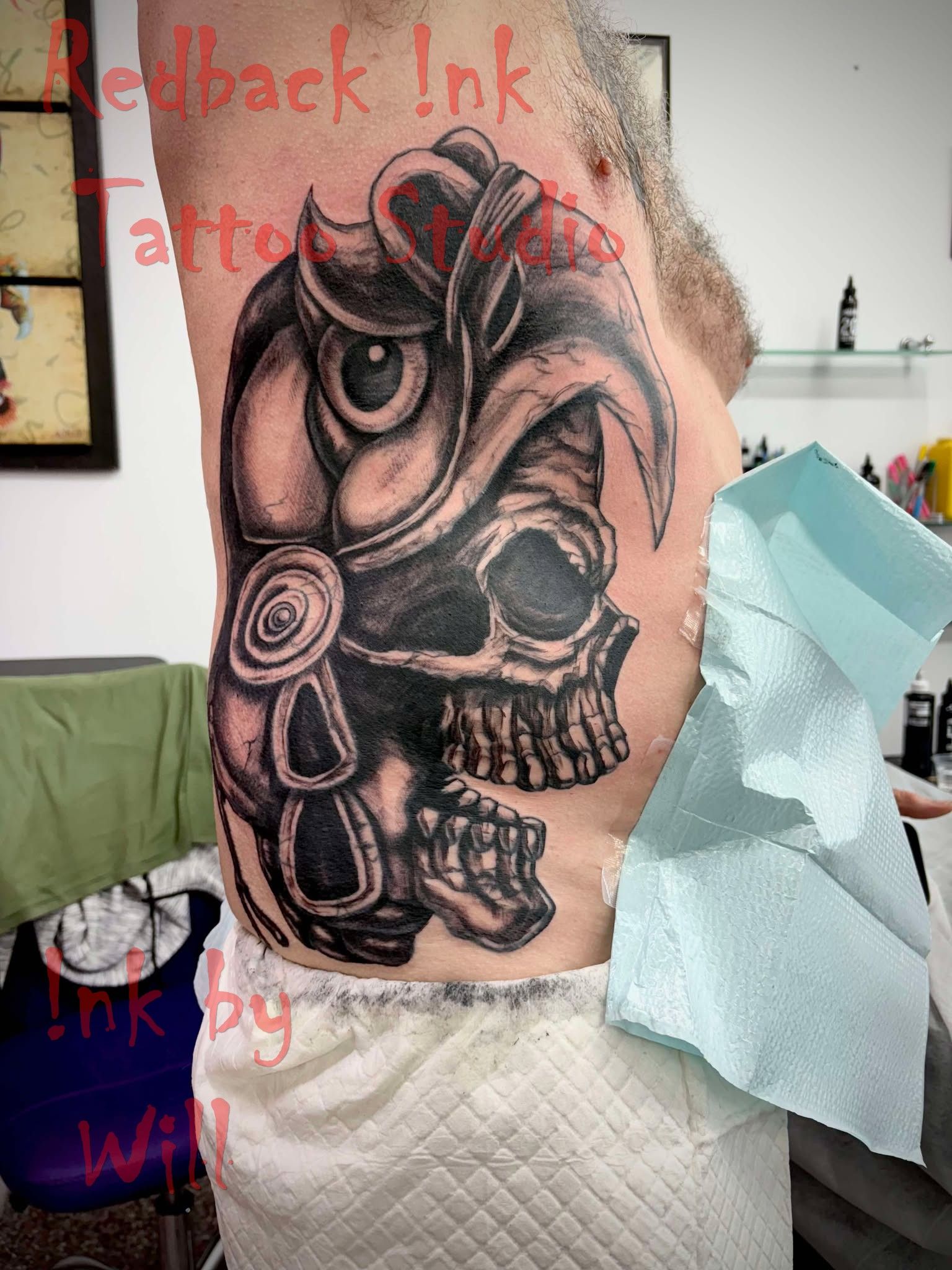 Tattoo on torso: Skull and owl design in black and grey shading. Person's side and abdomen visible.