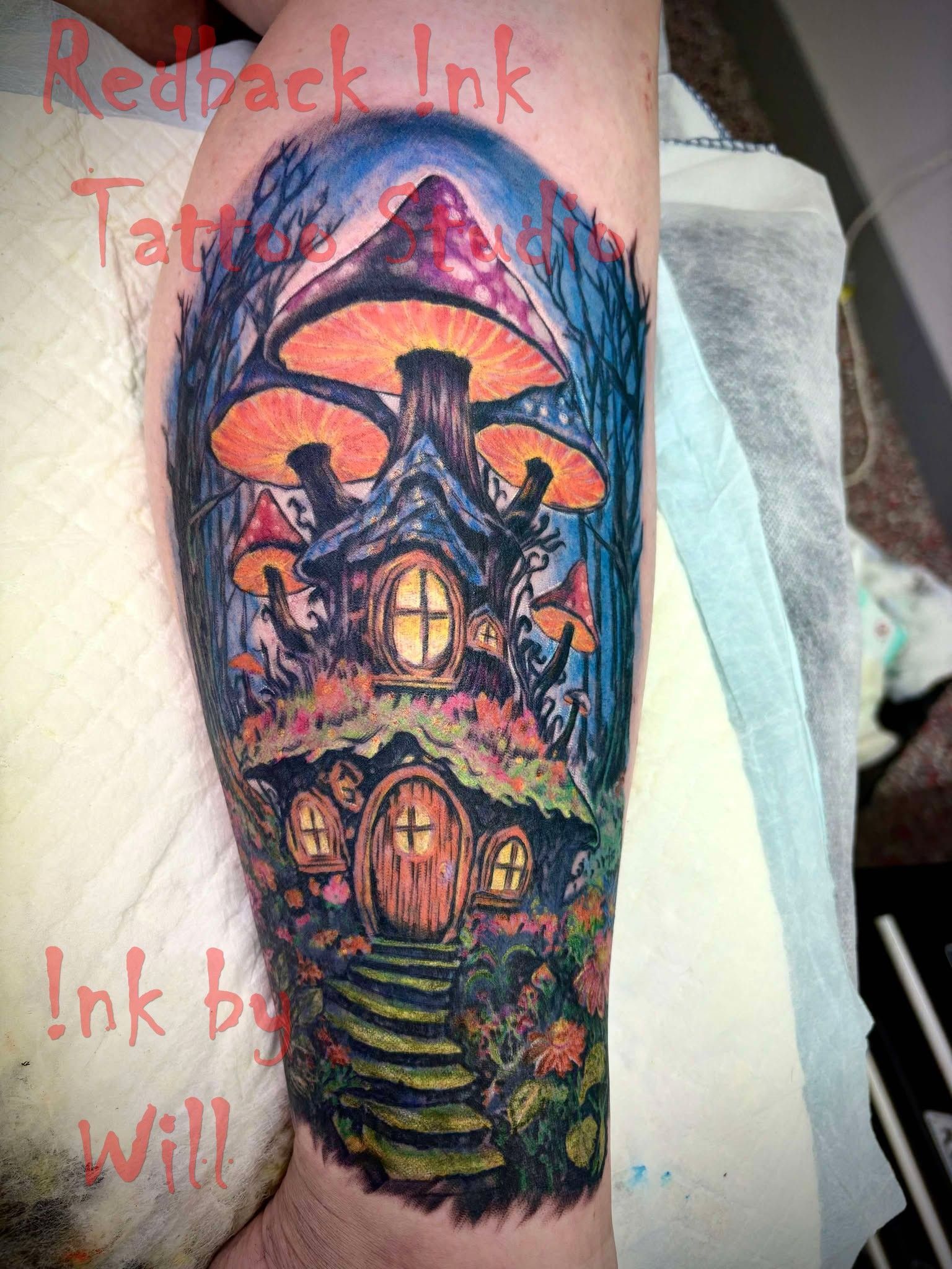 Colorful mushroom house tattoo on a person's leg, with trees, flowers, and a whimsical design.