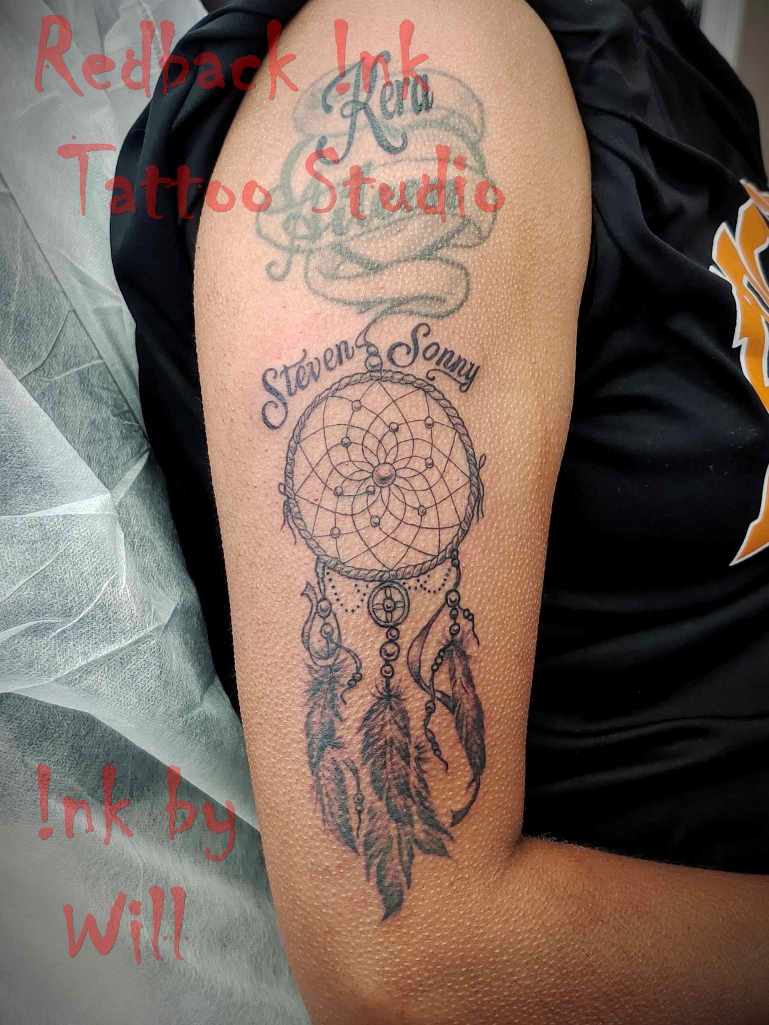 Tattoo on arm of dream catcher and names 