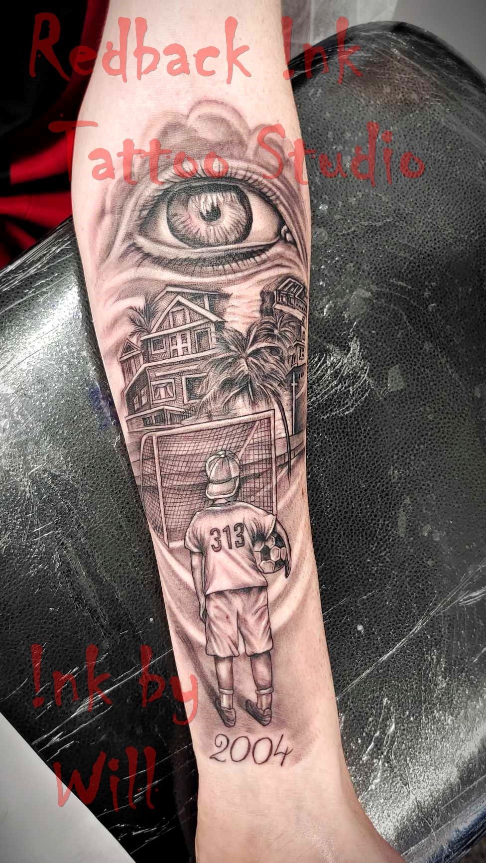 Tattoo of a soccer player with a ball, eye, ancient structures, and the year 2004.