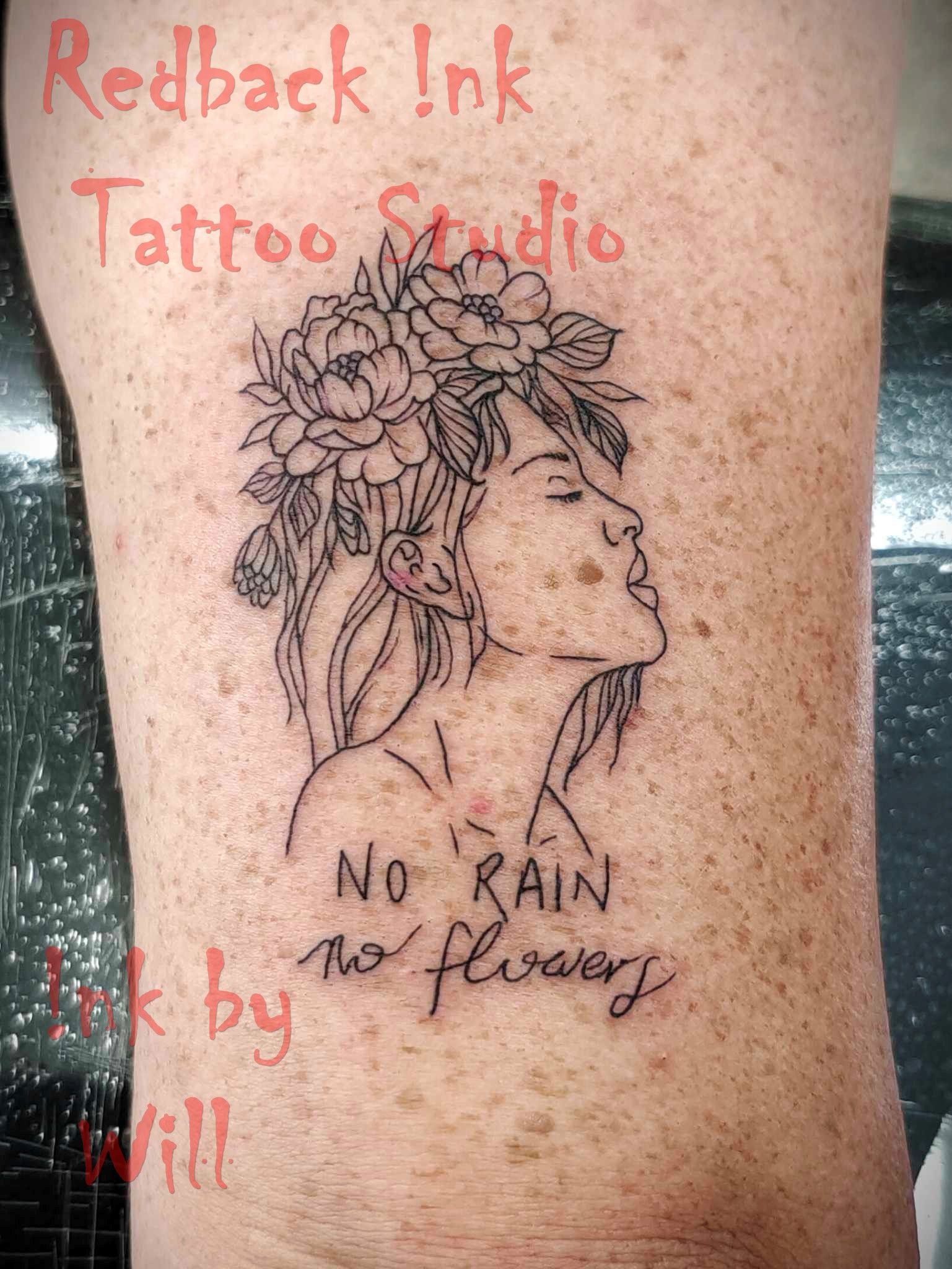 Tattoo of a woman with flowers in her hair, looking up, and the phrase 