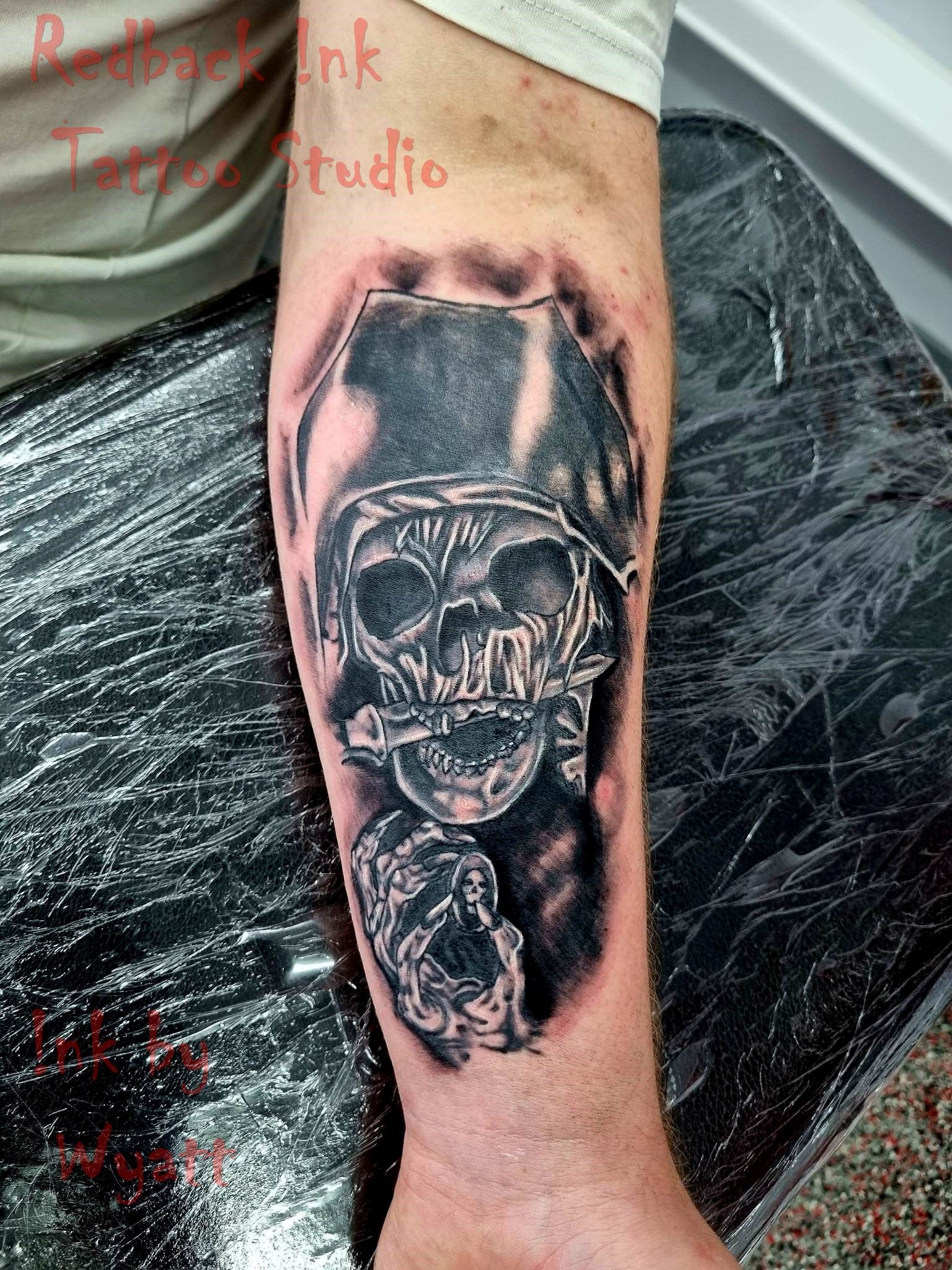Skull tattoo on forearm, black and gray shading. A second skull below. — Redback !nk Tattoo Studio in Kawana, QLD