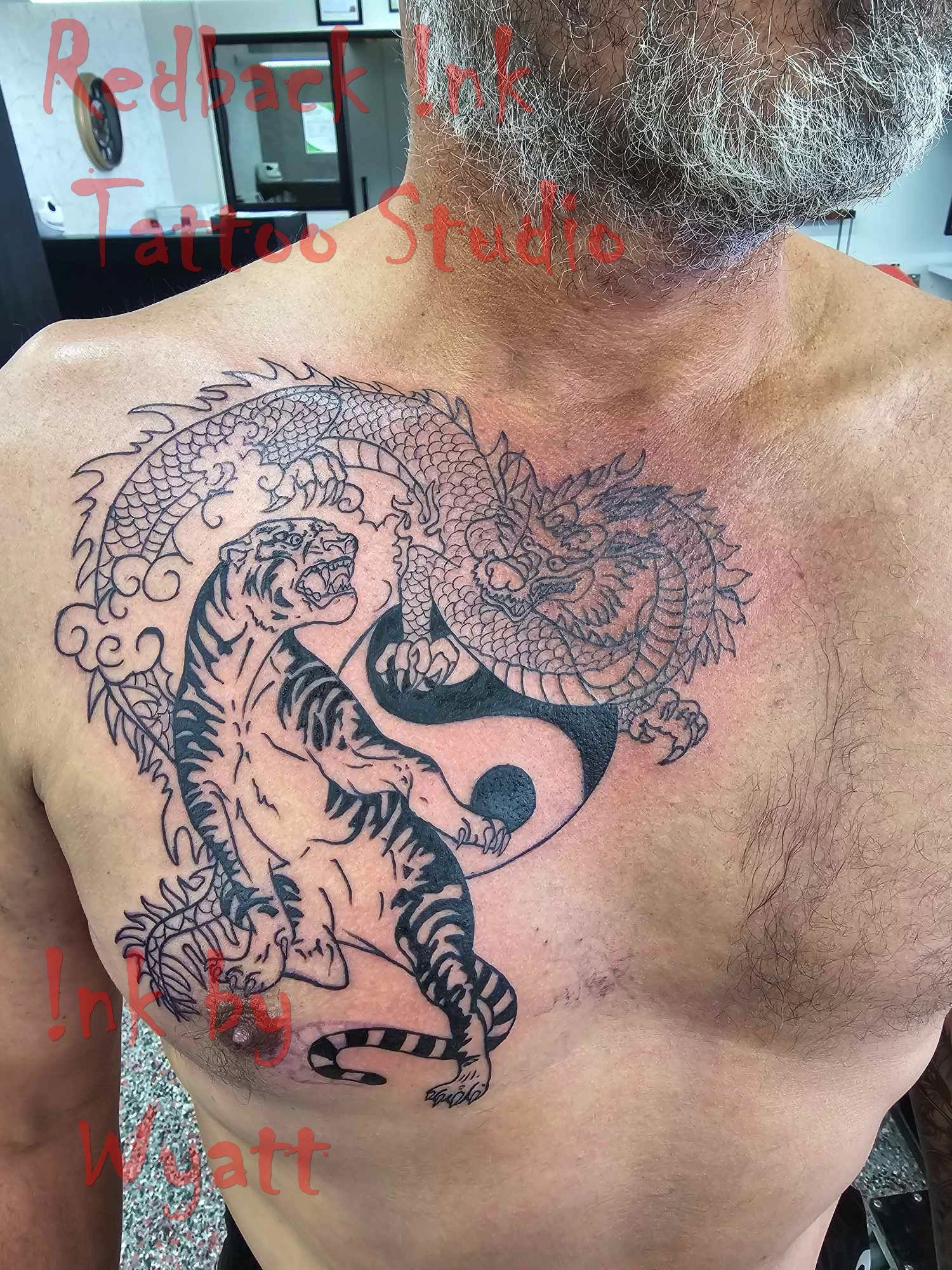 Man with chest tattoo of tiger, dragon, and yin-yang symbol. Tattoo is black ink. — Redback !nk Tattoo Studio in Kawana, QLD