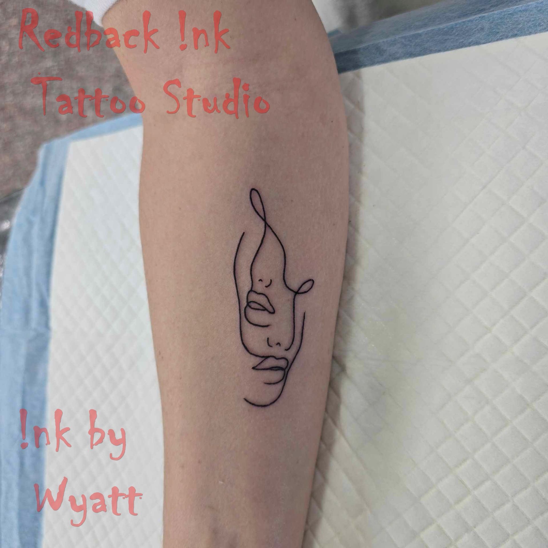 Black line art tattoo of two faces on an arm. 