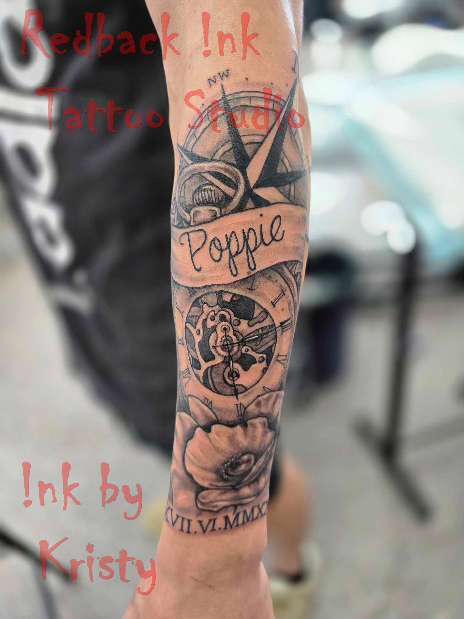 Black and gray arm tattoo with compass, banner reading 