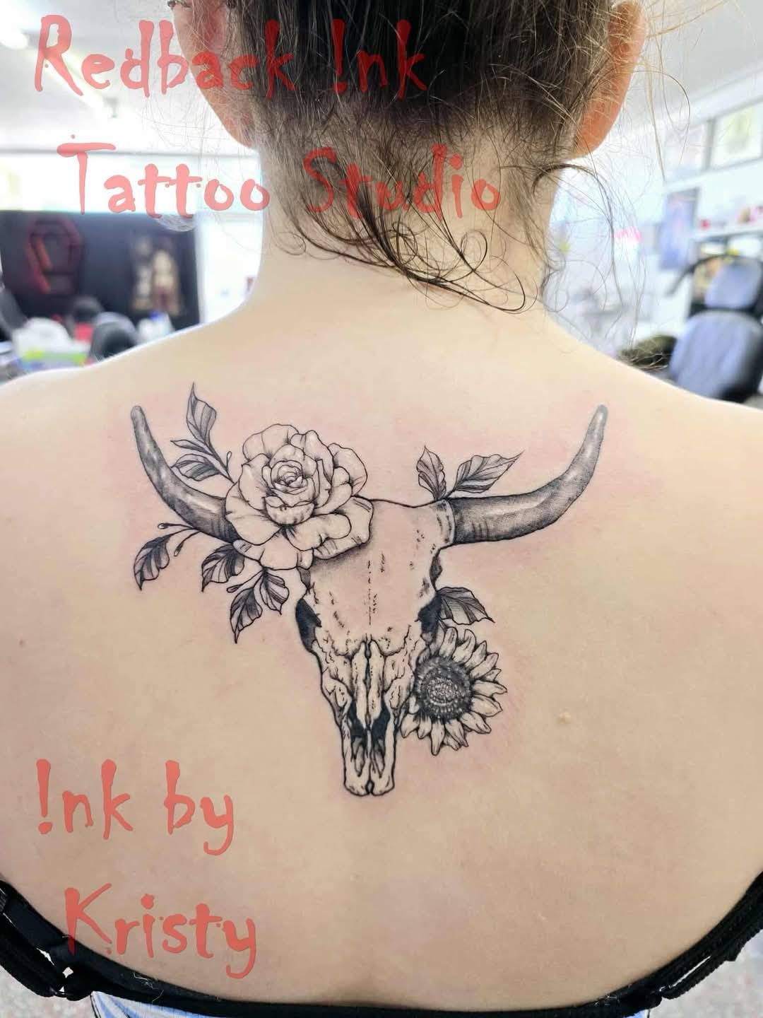 Back tattoo of a bull skull with a rose and sunflower. Studio name and artist's name in red — Redback !nk Tattoo Studio in Kawana, QLD