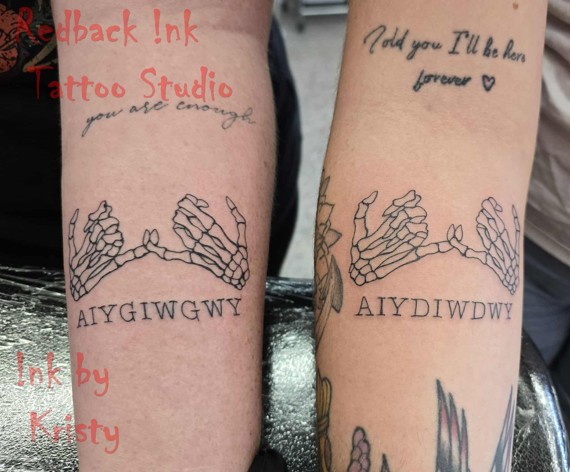 Two forearms with matching skeleton hand tattoos. Text above the hands and at the bottom. One arm says 