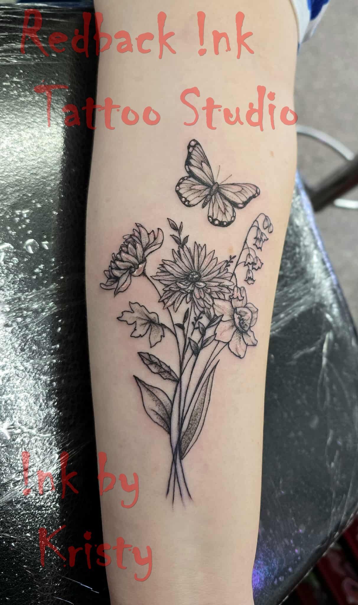 Tattoo of a flower bouquet and butterfly on a person's arm, done at 