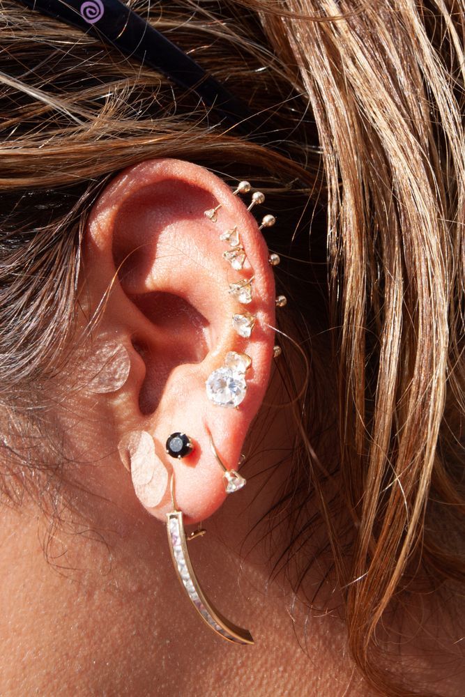 Ear With Multiple Piercings, Including Studs, a Black Stone — Redback !nk Tattoo Studio in Kawana, QLD
