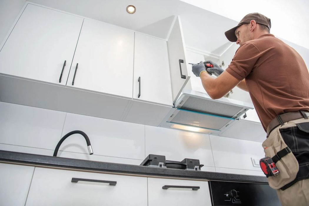 A man is installing a hood in a kitchen.