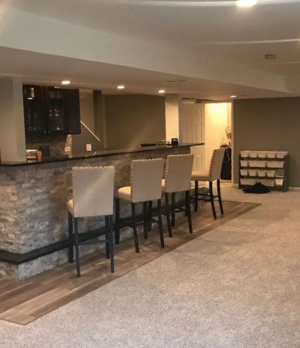 A basement with a bar and chairs in it