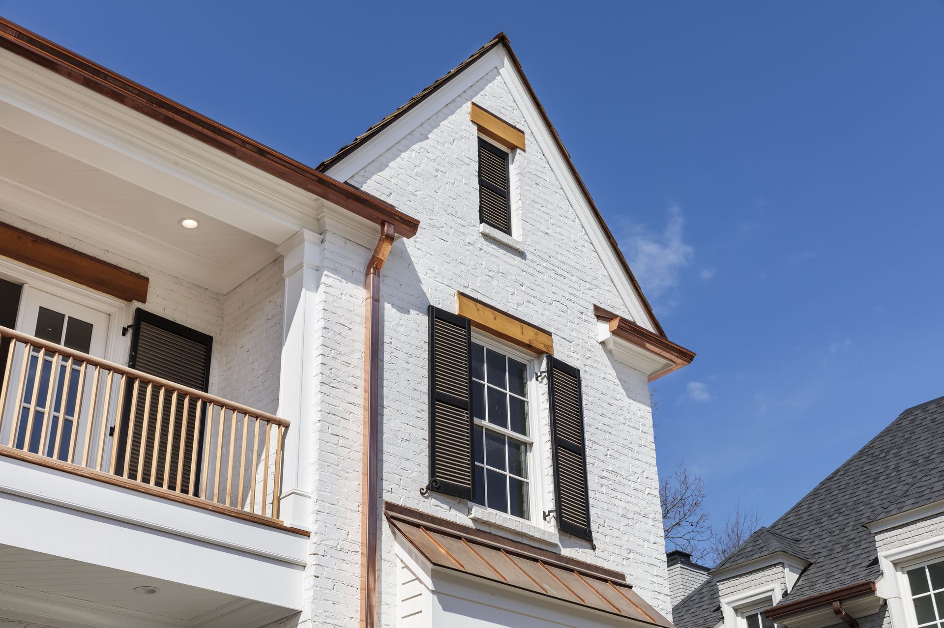 A white house with a balcony and a blue sky in the background.