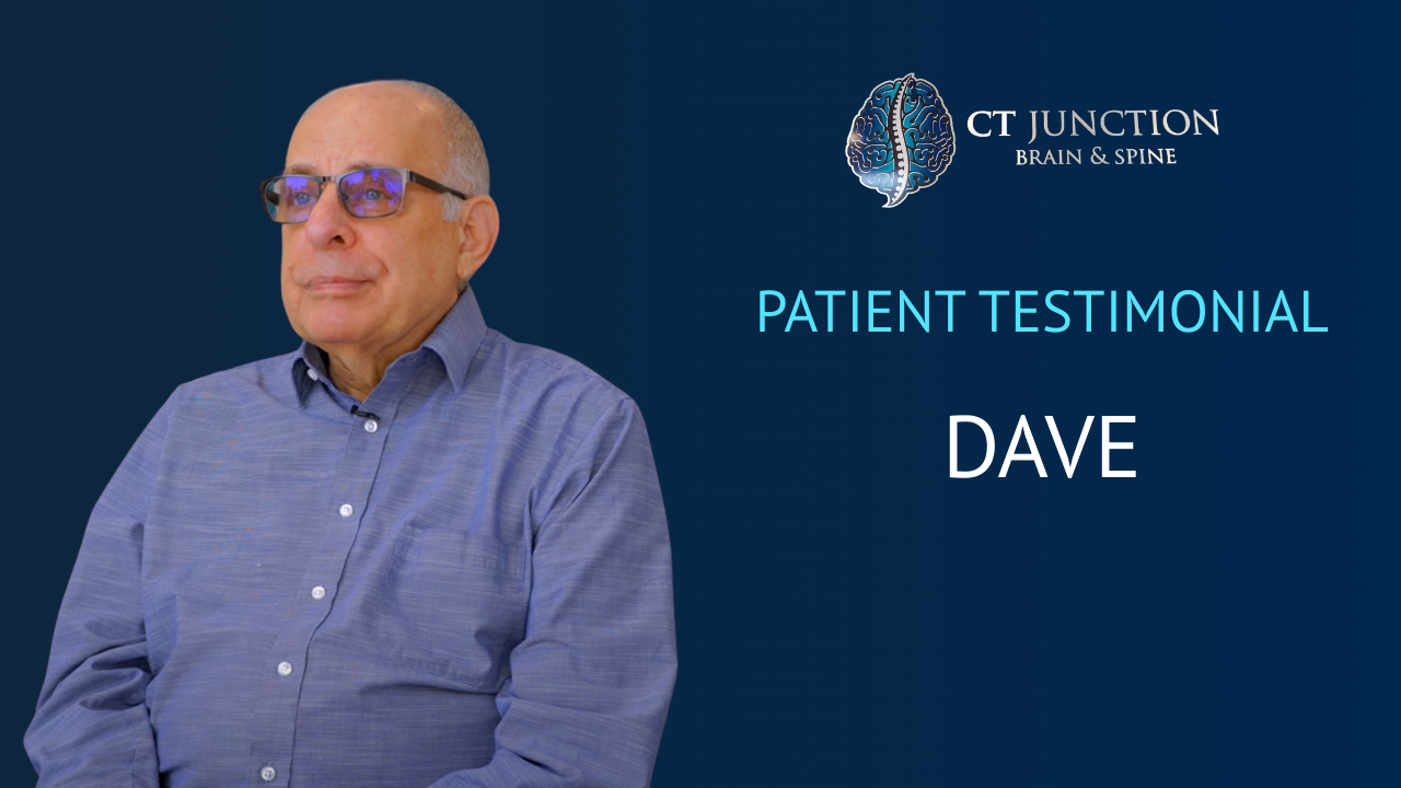Dave, a patient, giving a testimonial. He is wearing glasses and a blue shirt, with a dark blue backdrop.