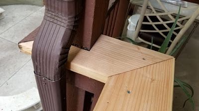 A wooden staircase is being built next to a brown gutter.