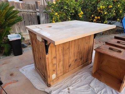 A wooden table is sitting on top of a white cloth on the ground.