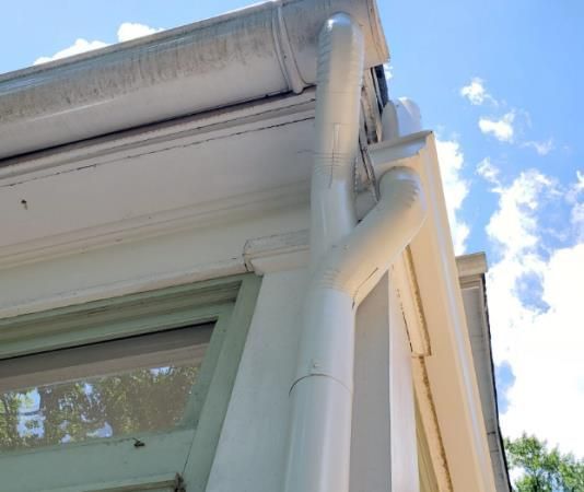White house exterior with a gutter system, sunny day.