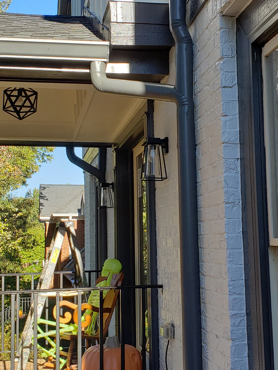Exterior of a house with a dark gray gutter, two hanging lanterns, and a small porch.