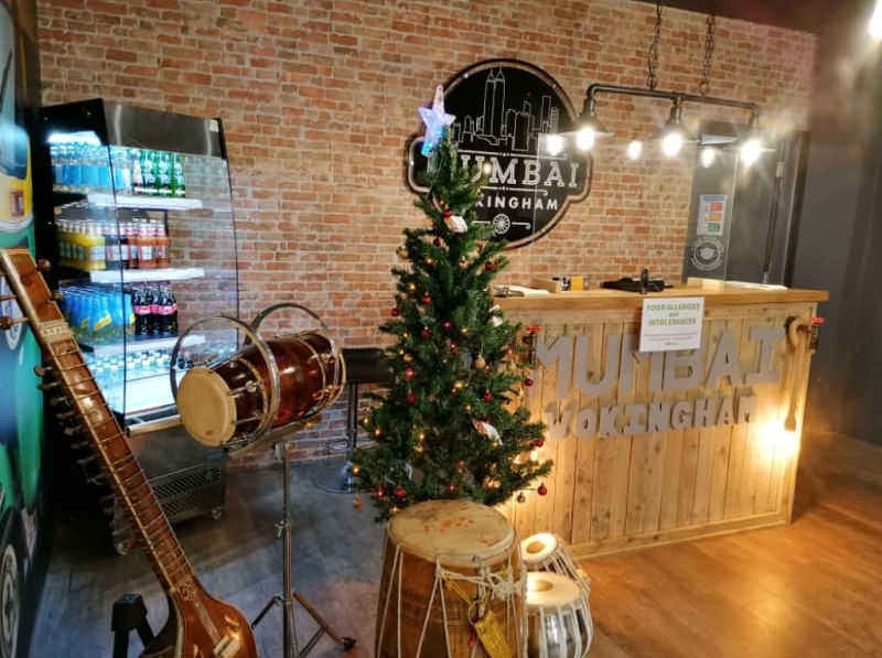 A christmas tree is sitting in front of a counter in a restaurant.