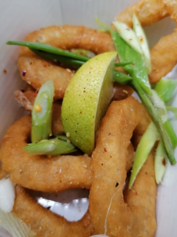 Fried onion rings with green onions and a slice of lemon