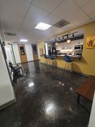 Open office space with a kitchenette, dark floors, yellow walls, and seating.