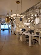 Interior of a lighting showroom, showcasing various modern chandeliers and desk area.