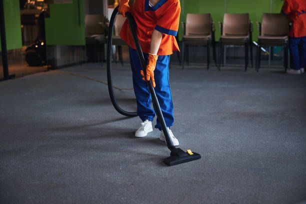 Janitor vacuuming carpeted floor in a conference room.