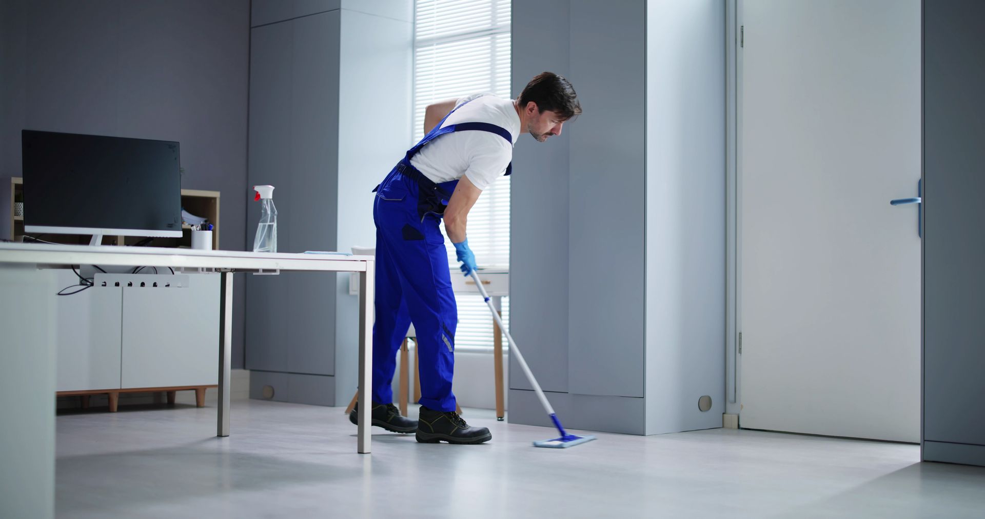 Male janitor cleaning and sanitizing office floors.
