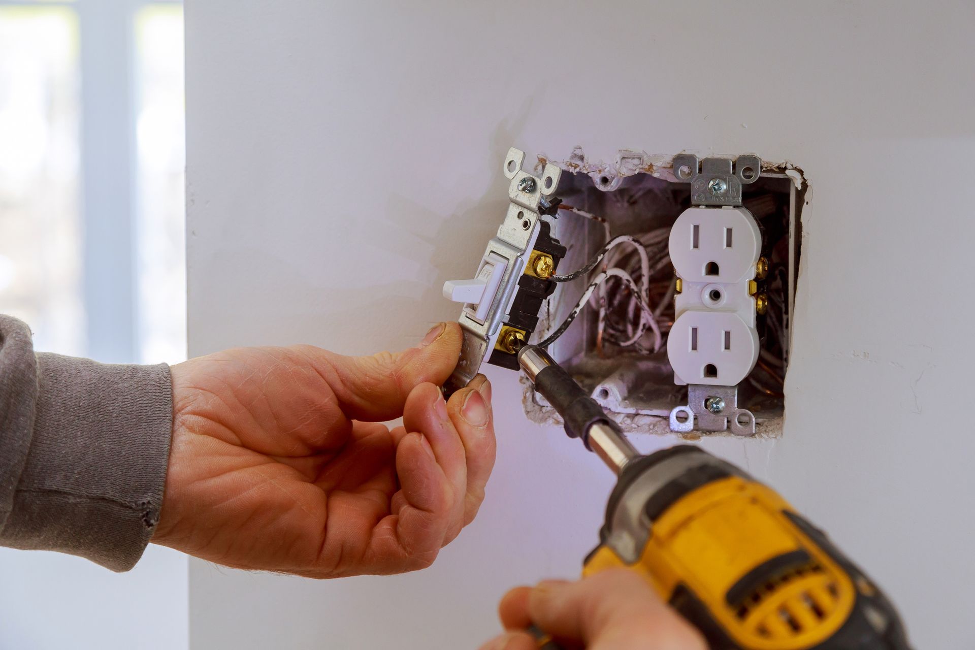 A person is installing an electrical outlet in a wall.