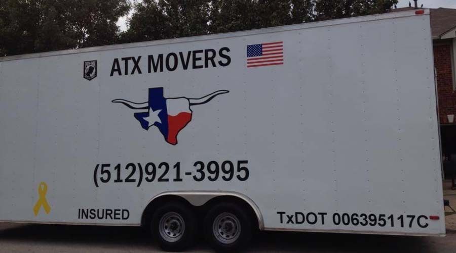 White ATX Movers trailer with Texas and US flags, phone number, and DOT number.