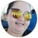 Uma mulher usando óculos escuros está sorrindo em um círculo.