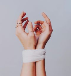 As mãos de uma mulher estão amarradas com uma bandagem