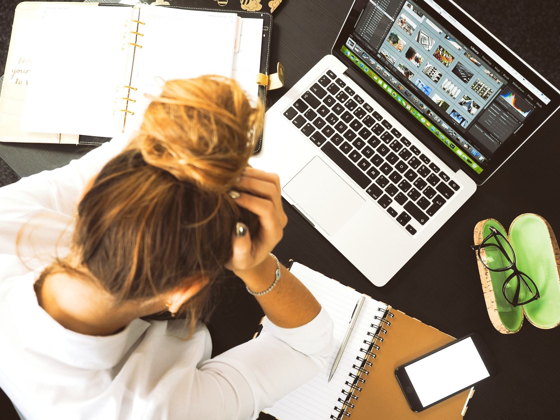 Uma mulher está sentada em uma mesa com um laptop e um telefone celular