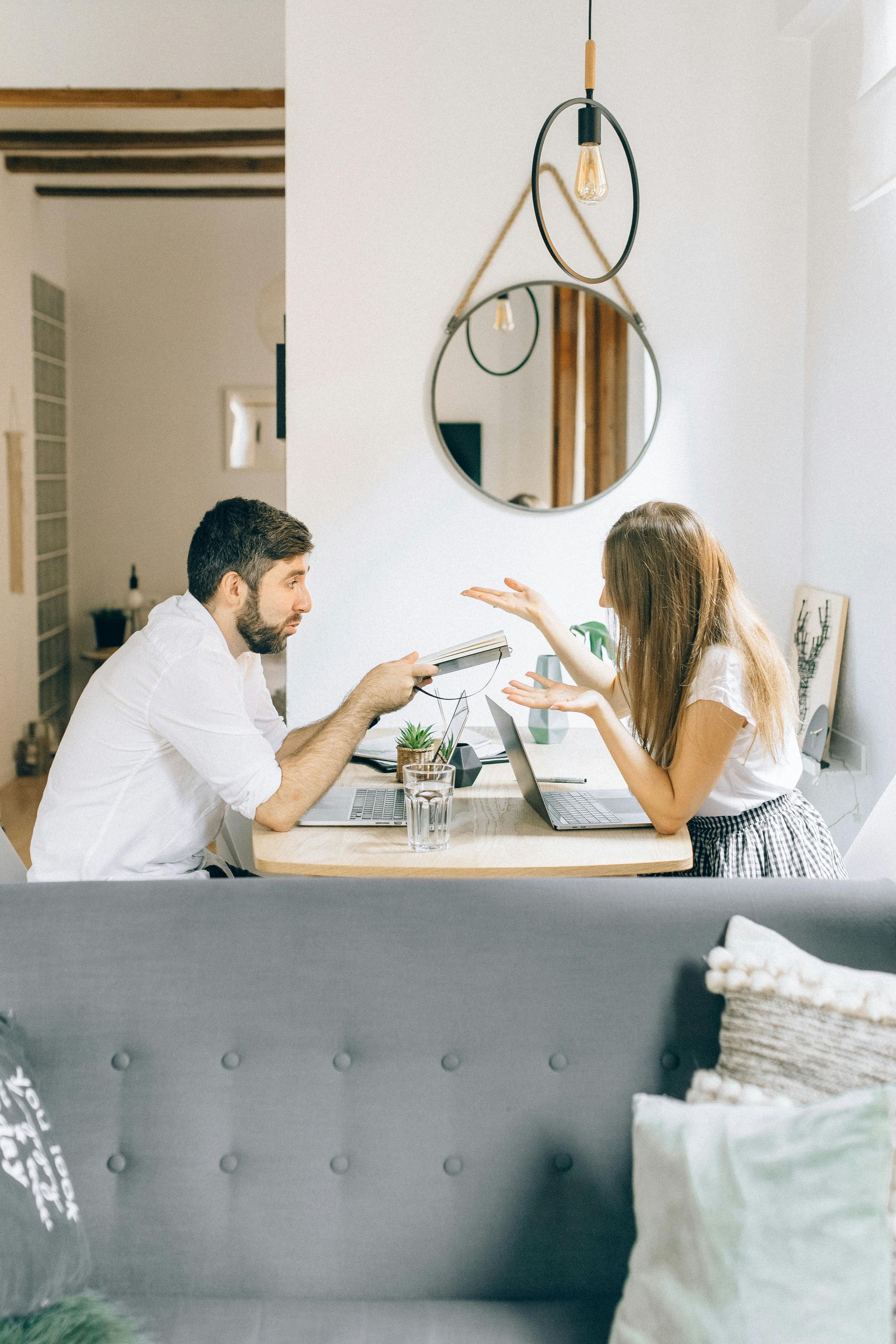 Um homem e uma mulher estão sentados à mesa em uma sala de estar.