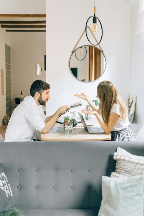Um homem e uma mulher estão sentados à mesa em uma sala de estar.