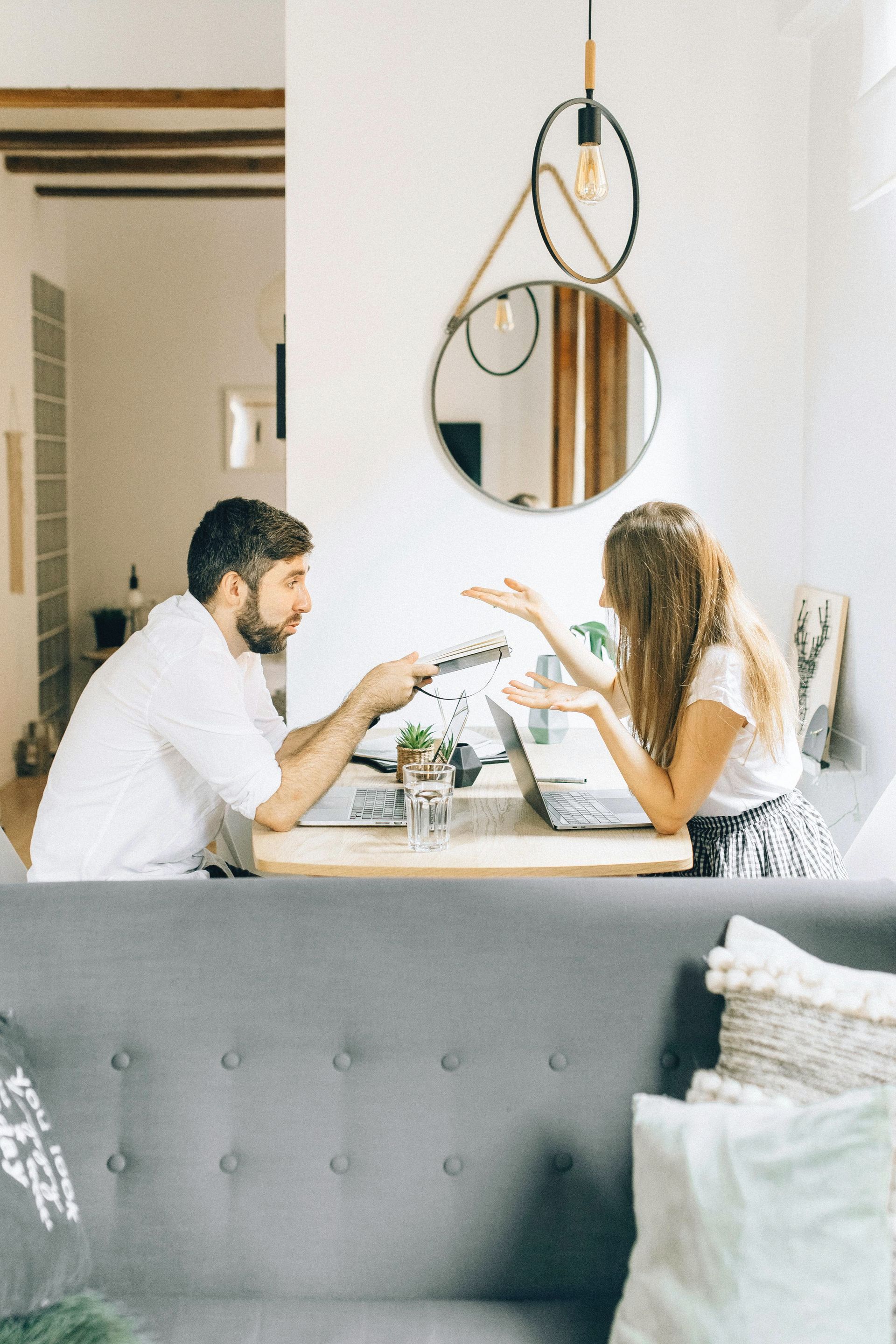 Um homem e uma mulher estão sentados à mesa em uma sala de estar.