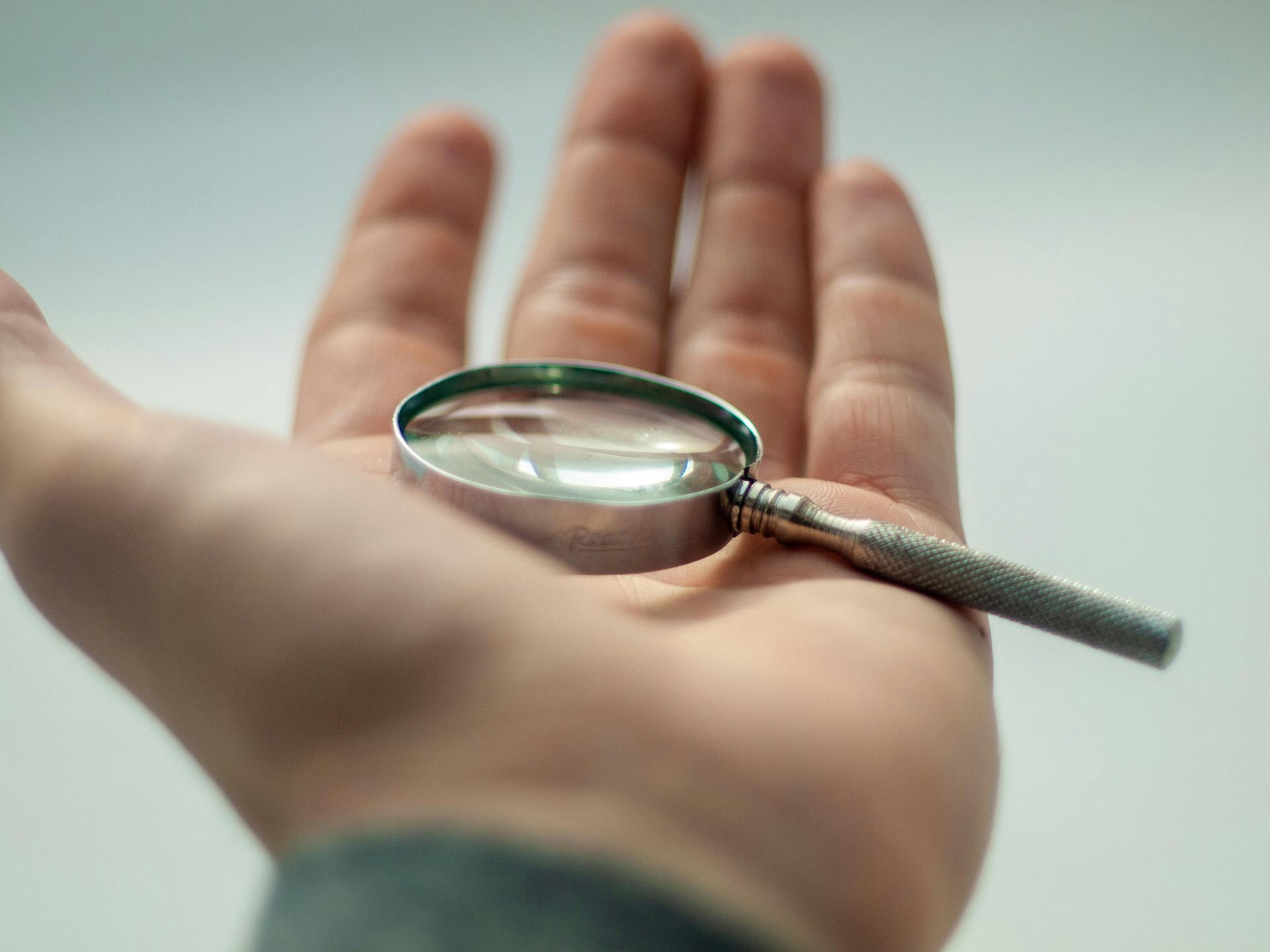 Hand holding a small magnifying glass, close-up view.