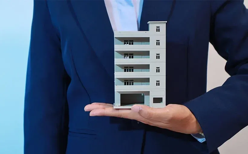 A man holding an apartment building model